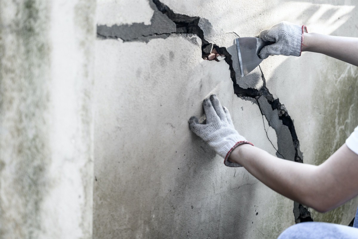 کارگر در حال ترمیم ترک در فونداسیون، نشاندهنده روشهای پیشگیری و تعمیر صحیح